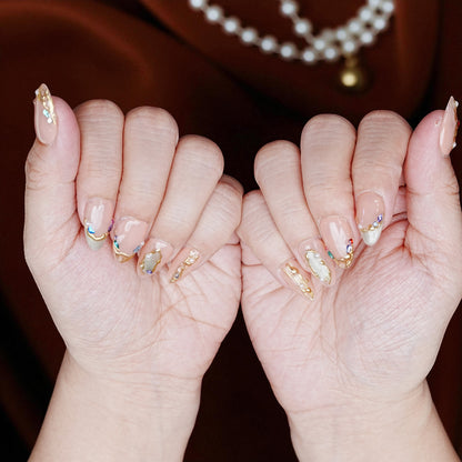 Almond-shaped blush chrome nails laid out on pastel background