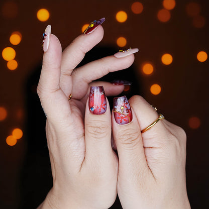 Two thumbs with red sparkle press on nails showing Christmas chain art and snowflake glitter designs