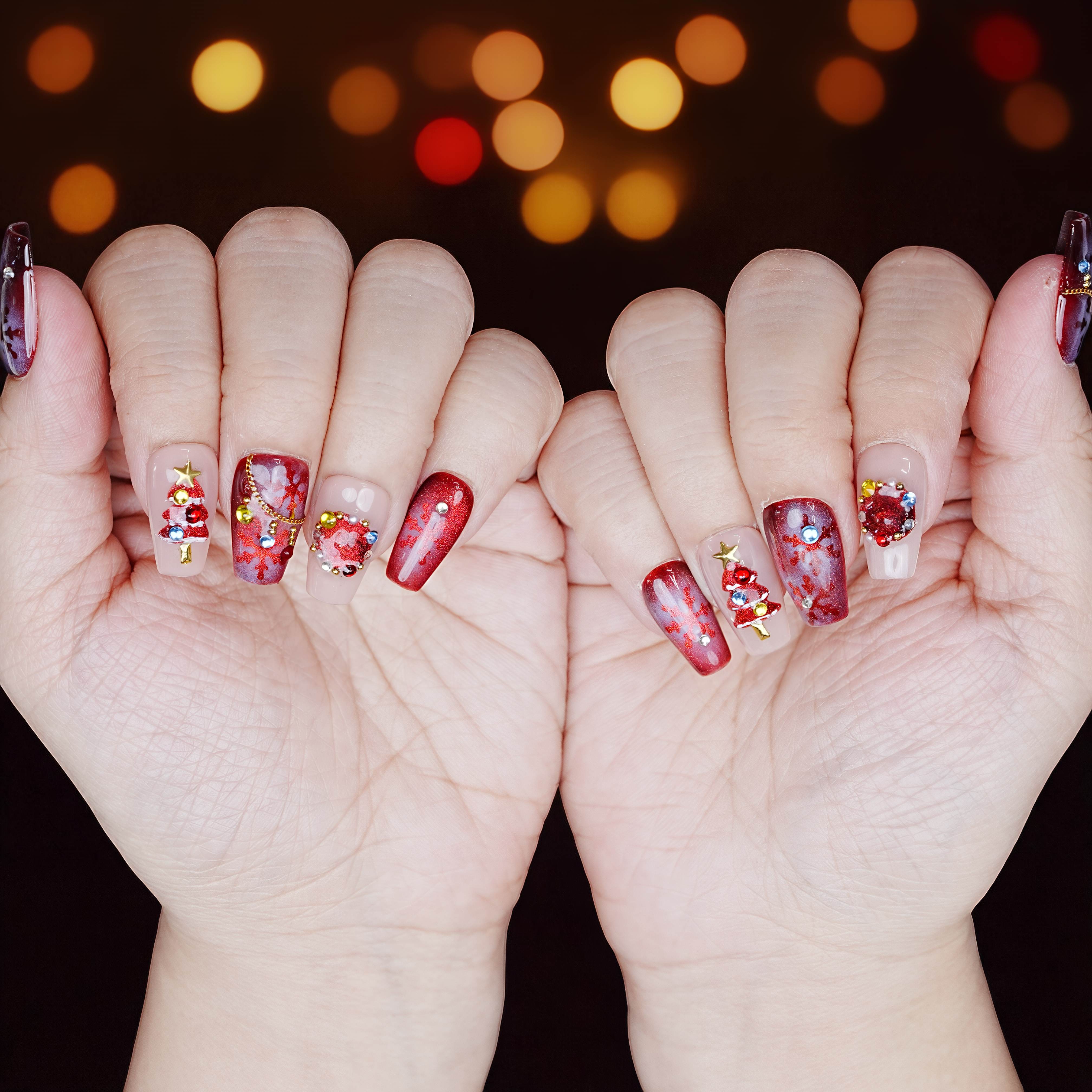 Matching hands wearing long red Christmas press on nails with tree and gem wreath designs