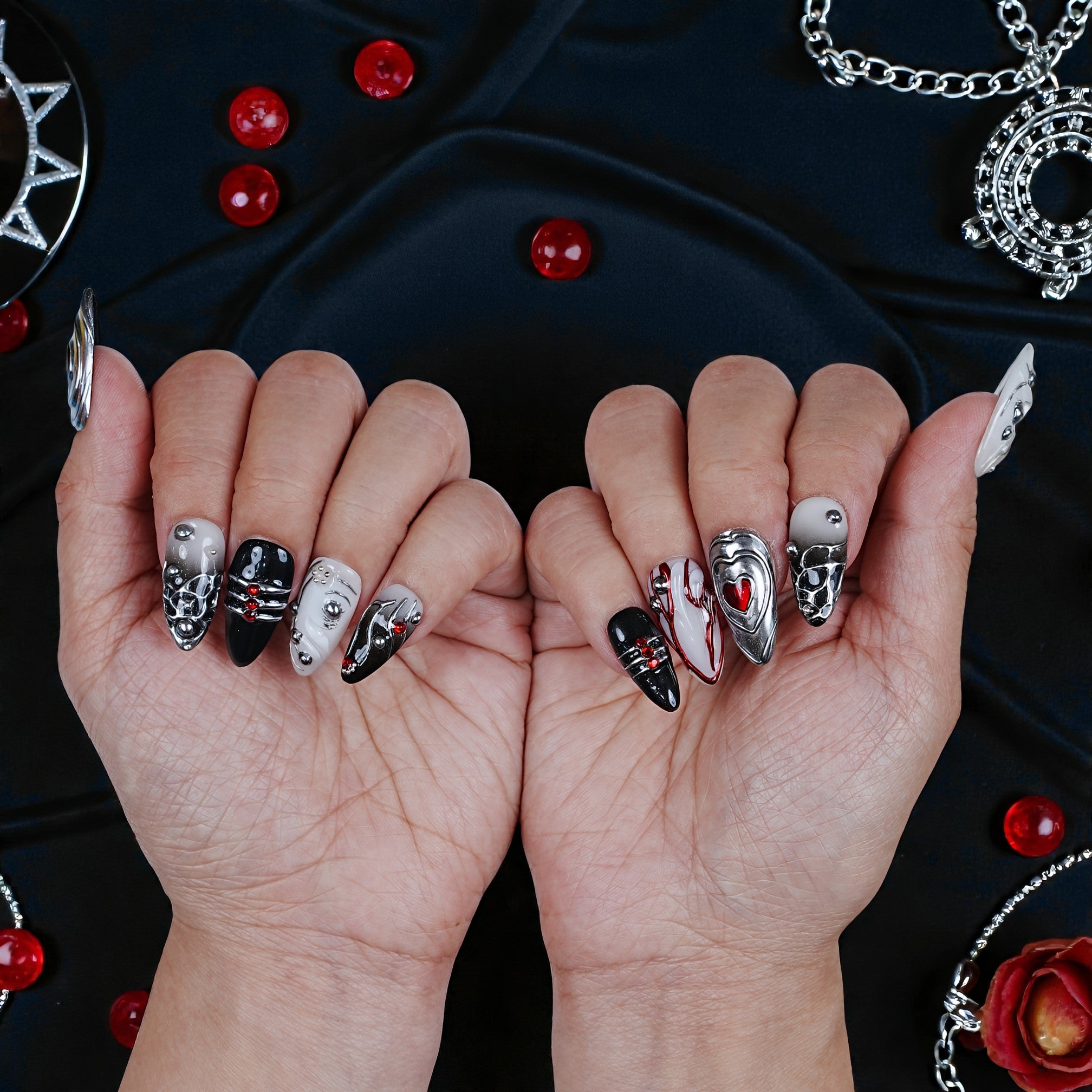 Handmade black, silver, and red press on nails with 3D heart and gem accents on hands