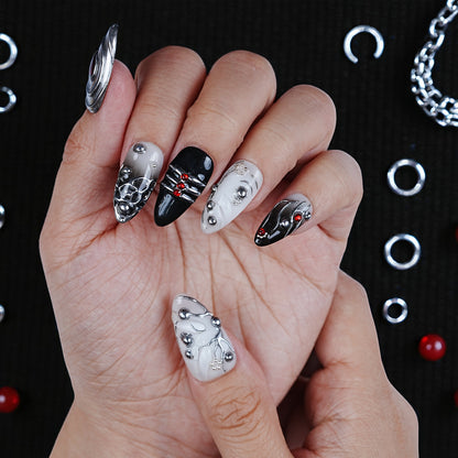 Hand with metallic 3D press on nails in black, silver, and white, with red gem accents