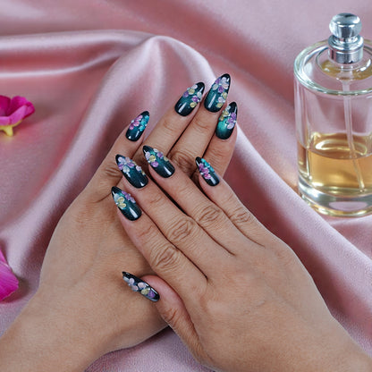 Hand with premium handmade press on nails featuring floral design on a pink satin background