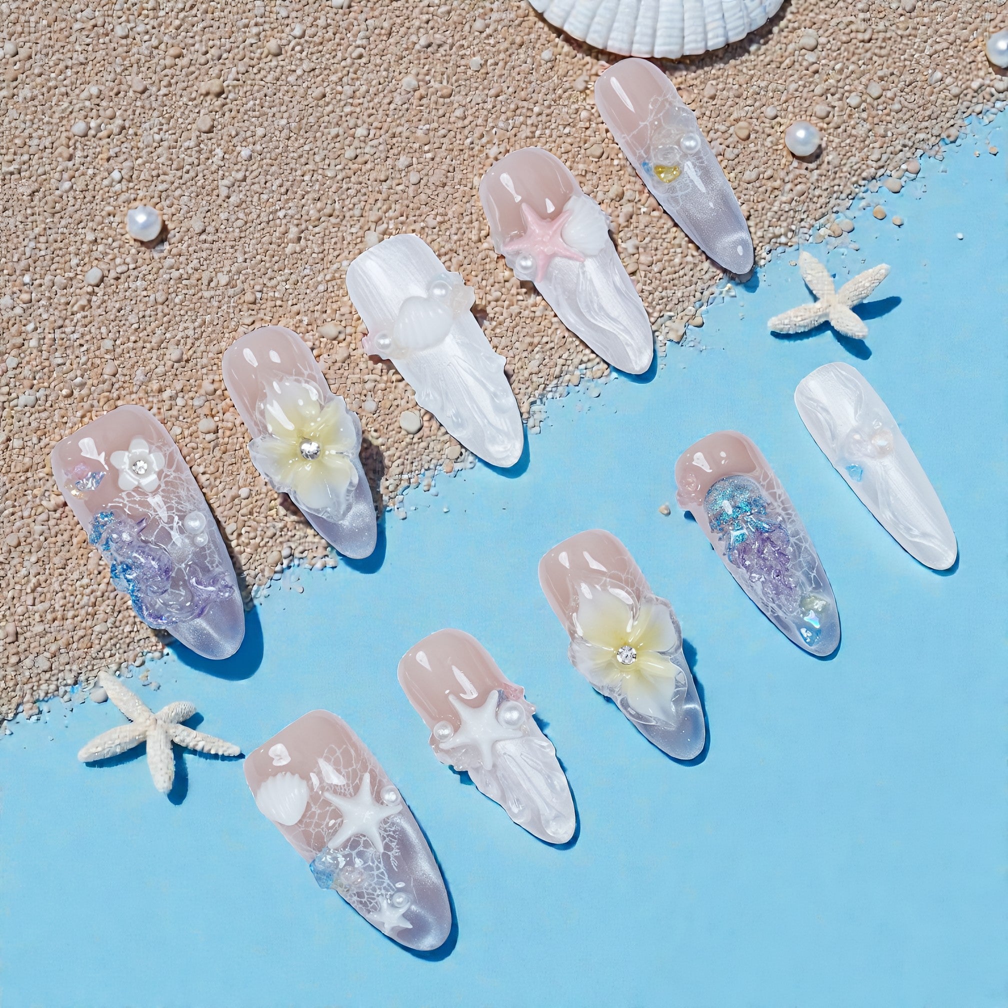 Handmade ocean-themed press on nails with 3D shells, flowers, and pearls on sand and blue background