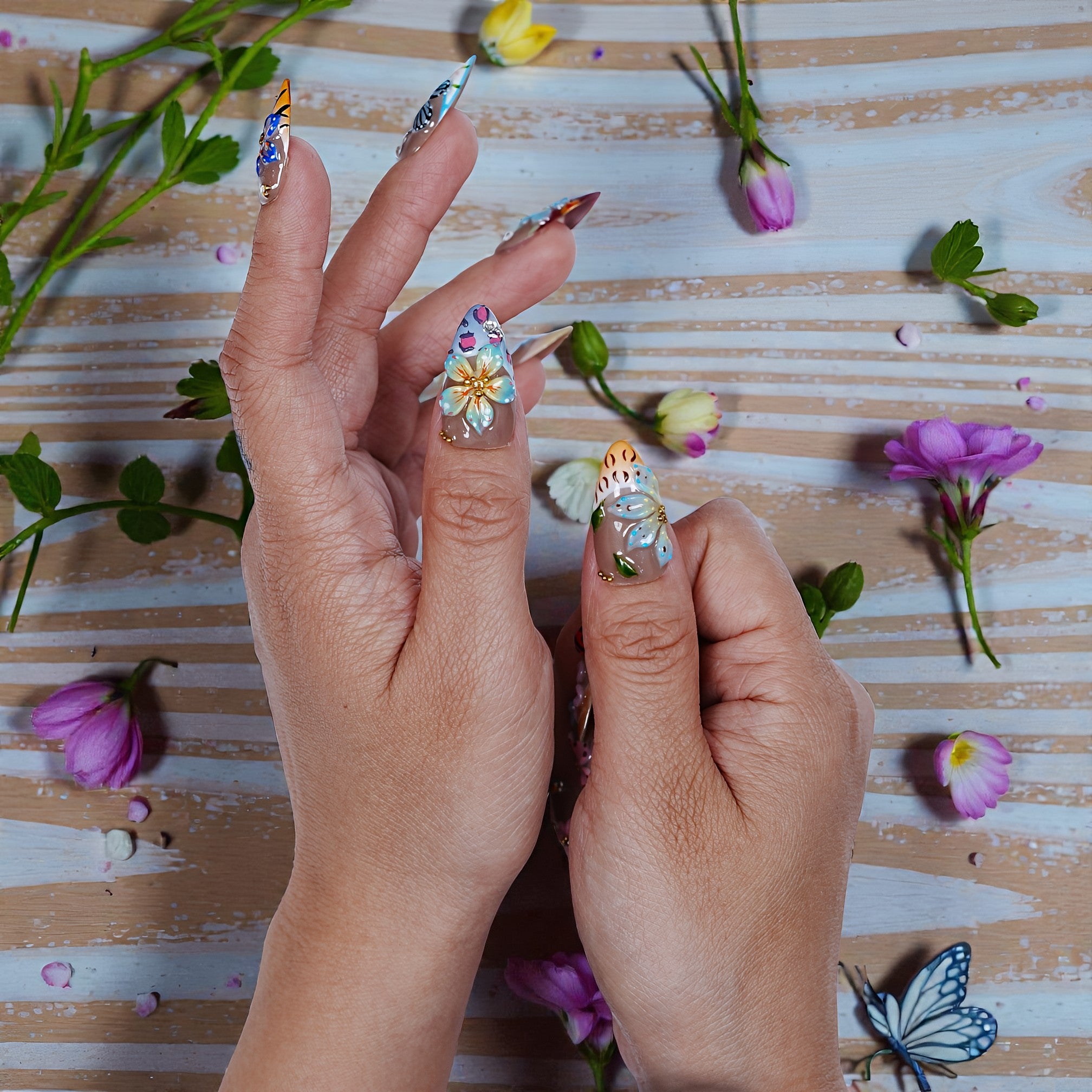 Hand displaying premium handmade floral press on nails with colorful 3D designs, surrounded by flowers