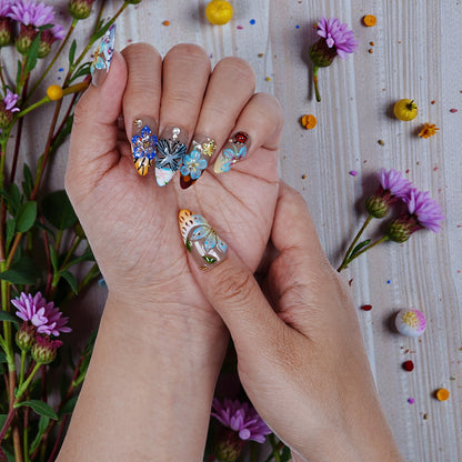 Hand displaying premium handmade press on nails with floral 3D art, surrounded by flowers