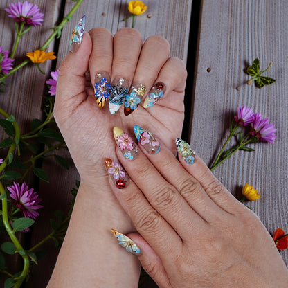 Handmade press on nails with 3D floral and butterfly designs on wooden background with flowers