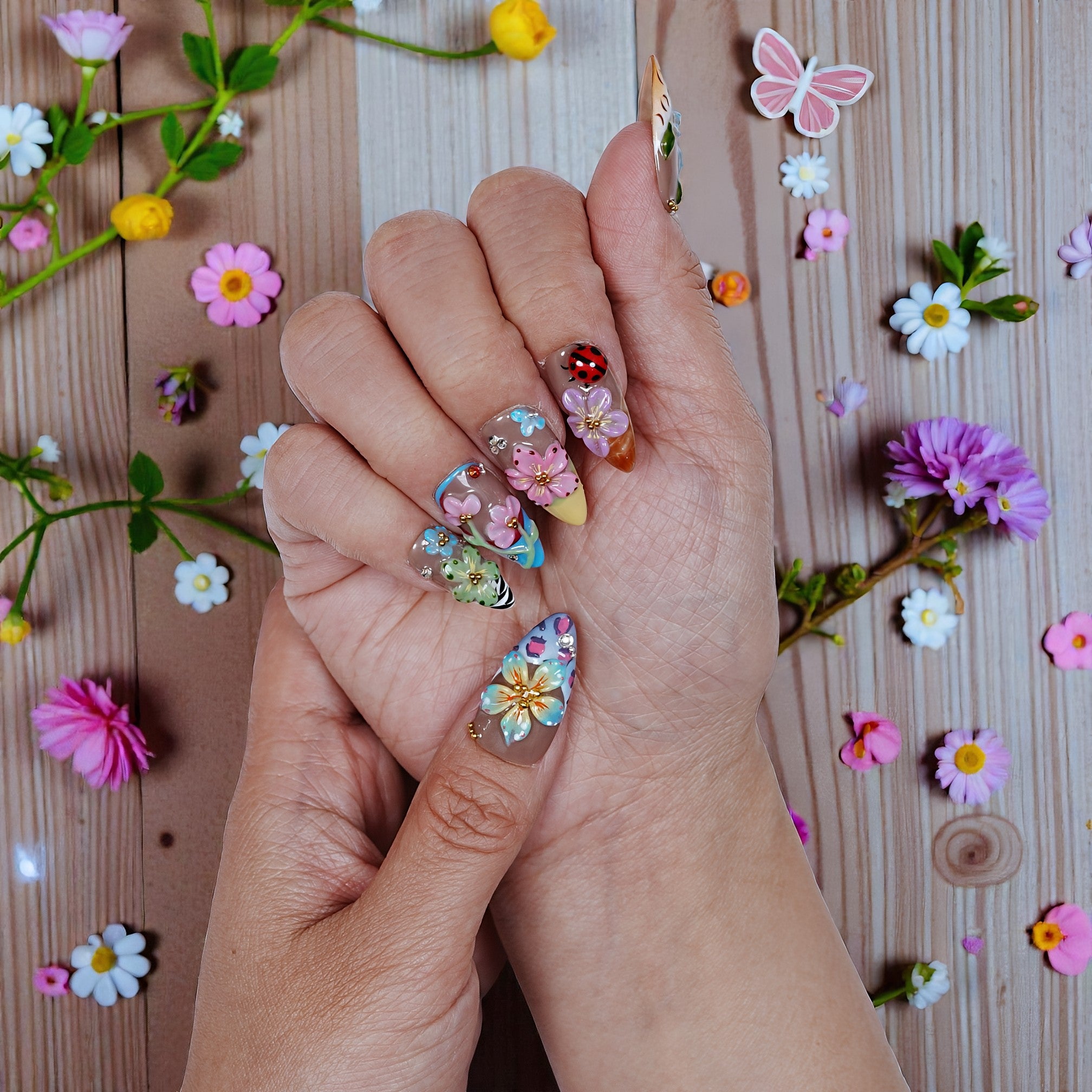 Hand with colorful floral press on nails, surrounded by flowers, Dress For Nails Australia