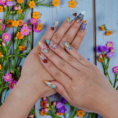 Hands with premium handmade press on nails featuring floral and butterfly designs, surrounded by flowers