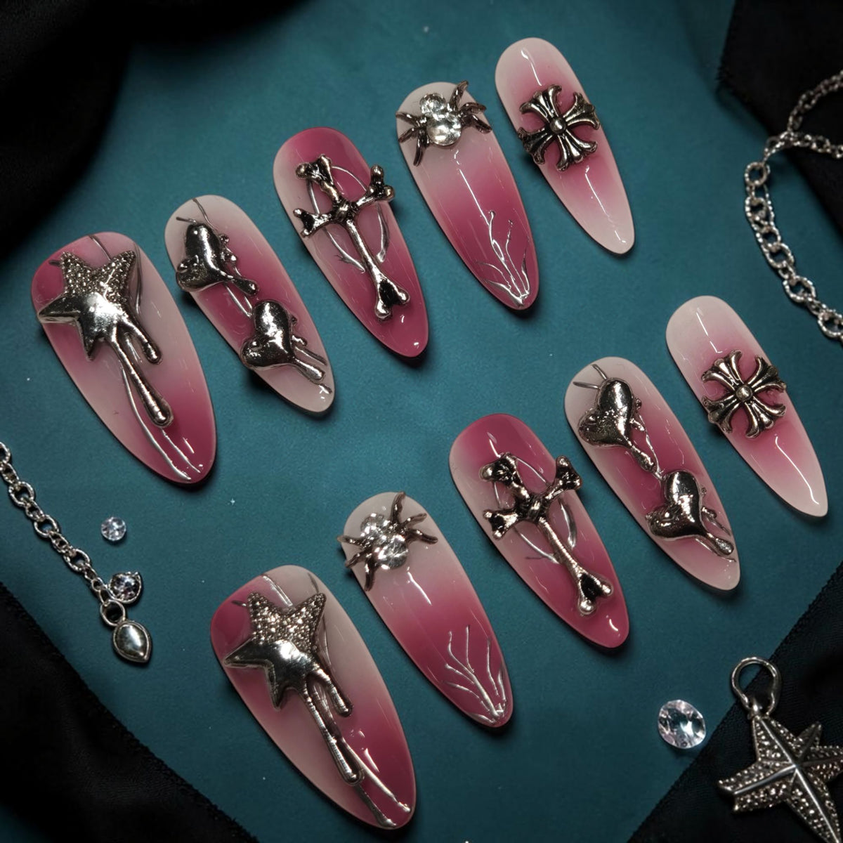 Bubblegum Goth pink goth press on nails with silver spider, cross, star and dripping heart charms on a pink ombre almond