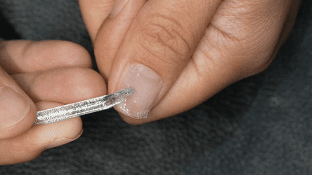 Using a cuticle tool to remove leftover nail adhesive after press on nail removal