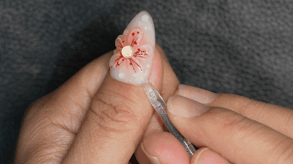 Gently lifting a press on nail using a cuticle tool during the removal process